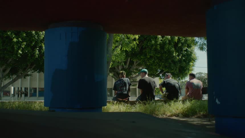 A group of young men talk with one another while sitting together outdoors