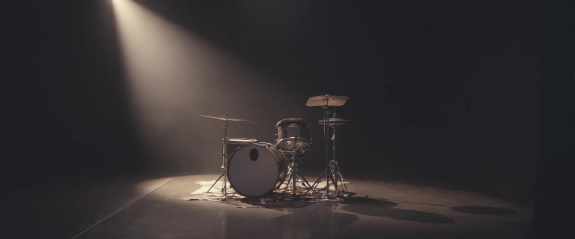 A spotlight shines on a drum kit on a stage