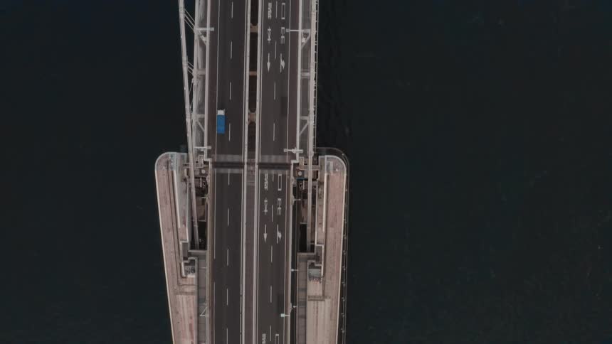 Traffic moves in both directions across four lanes of a bridge over water