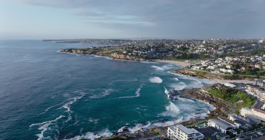 Large houses sit near beach in seaside town as waves roll onto shore