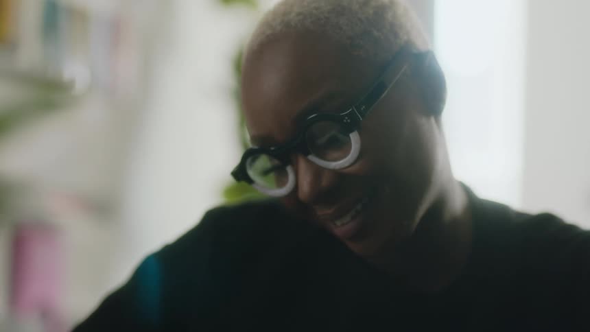 A woman with short blonde hair looks downward and smiles while turning her head