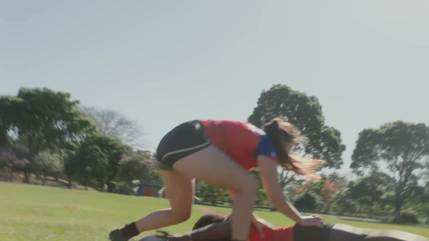 A group of girls are running and playing rugby on a sports field