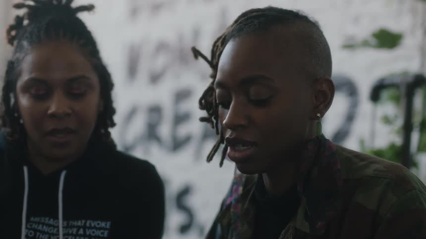 Two women brainstorm in an office with motivational words on the wall