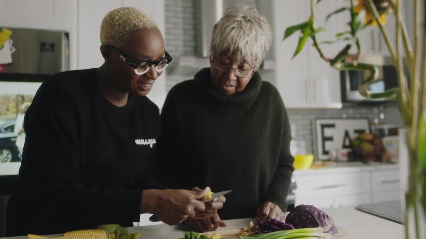 Woman smiles while cooking with elderly relative