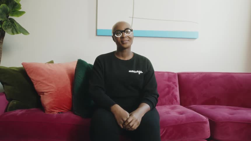 Woman poses sitting upright on brightly colored couch