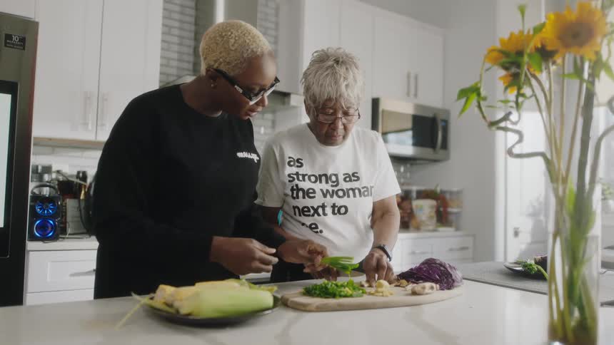 A pair of woman prepare vegetables together in a home kitchen during the day