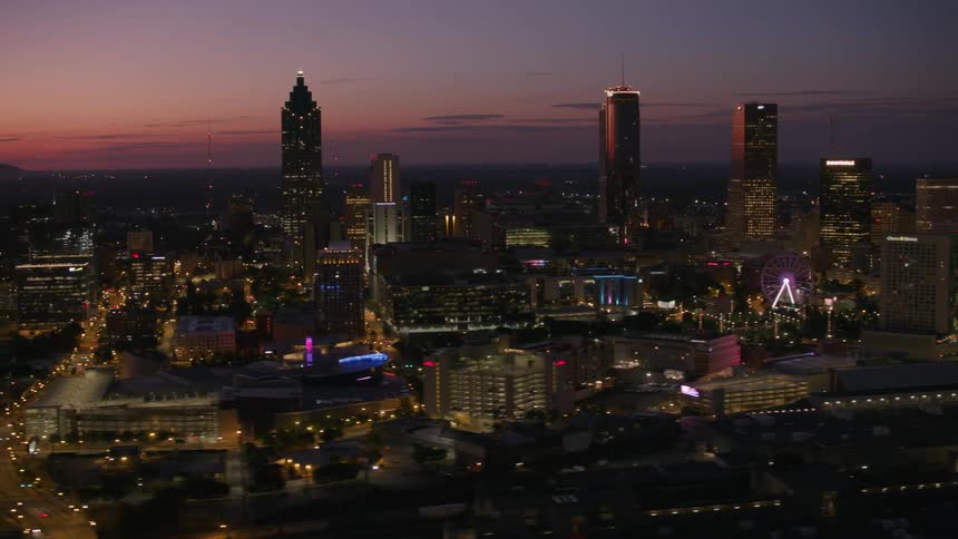 Aerial view of city skyline with illuminated skyscrapers and high rise buildings at dusk