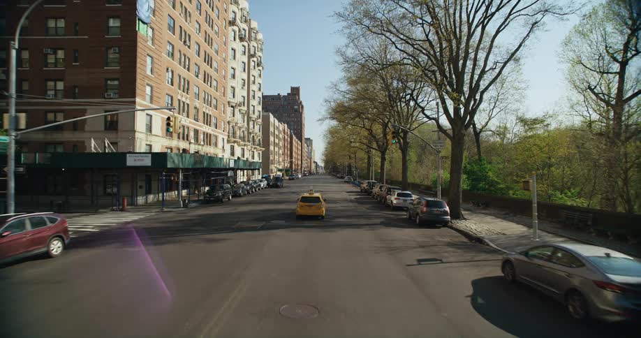 A yellow taxi drives down a quiet city street