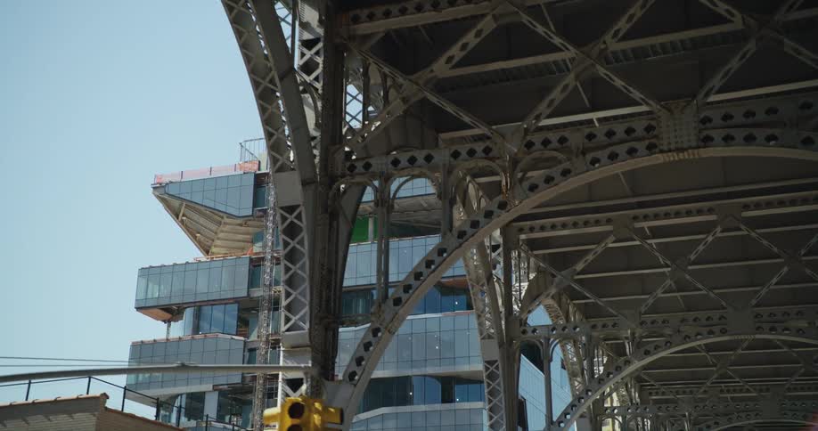 An apartment building is under construction near a tall bridge downtown
