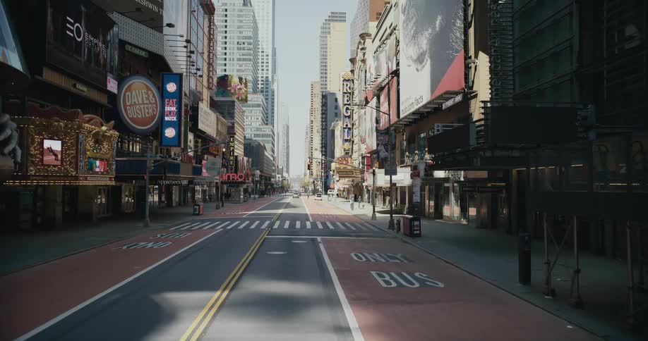 Pedestrians and vehicles move along city street bordered by businesses