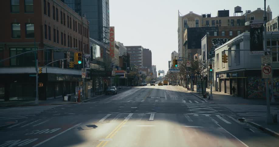 The apollo theater sign above an empty new york city street with only a couple of people walking