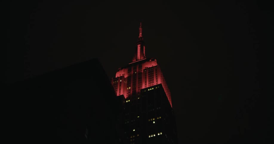 Skyscraper with spire lights up red at night