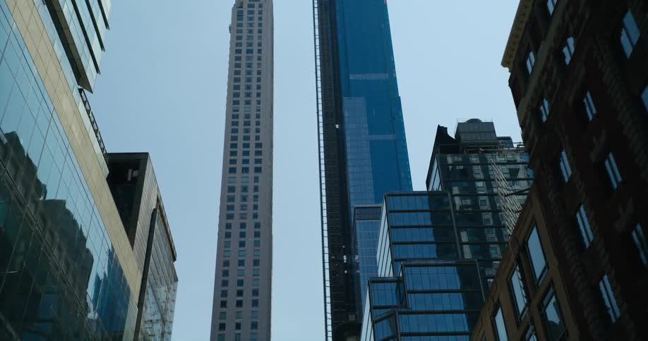 Very tall towers at the end of a downtown street reach high into a clear blue sky