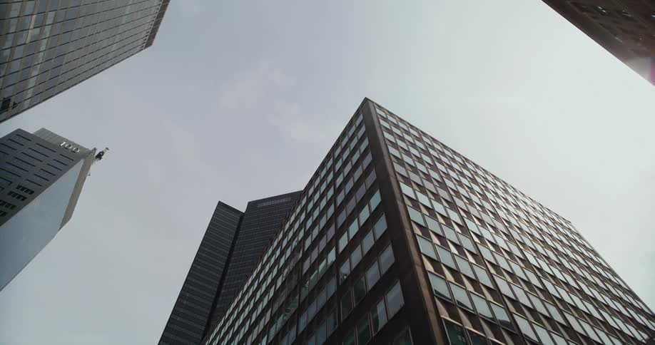 A view looking up at tall downtown buildings under a cloudy sky