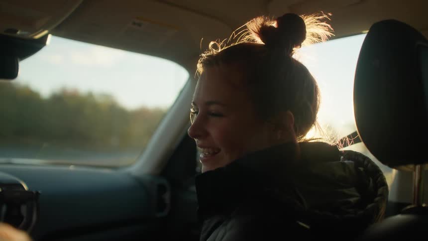 A woman smiles happily at the driver as they travel on a sunny day