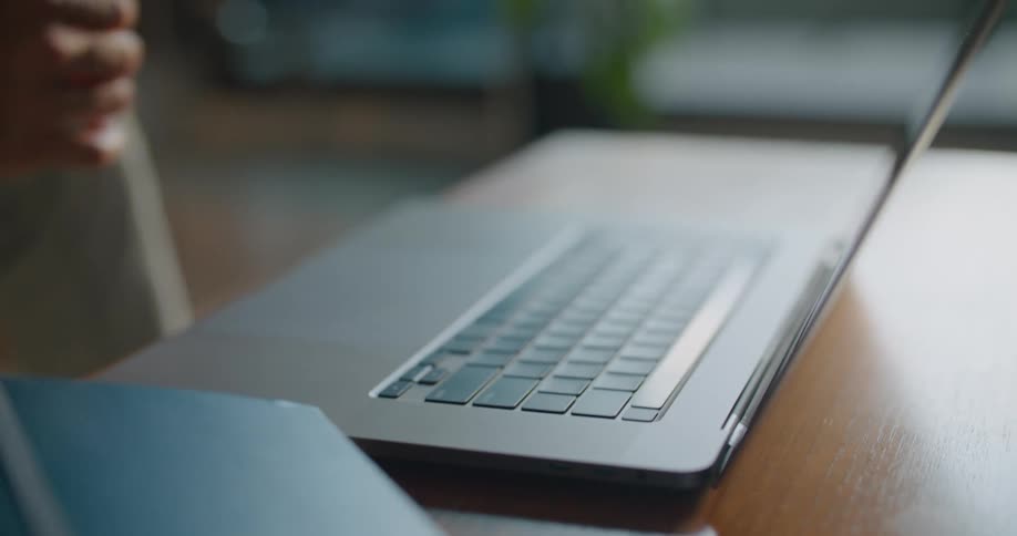 Man types on laptop sitting on wooden table