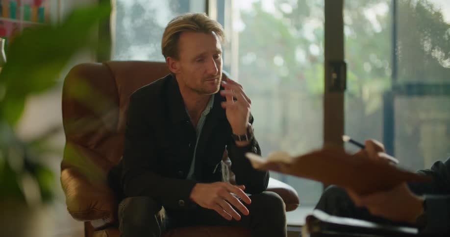 A man begins to get emotional while listening to another who holds up a journal to show him notes