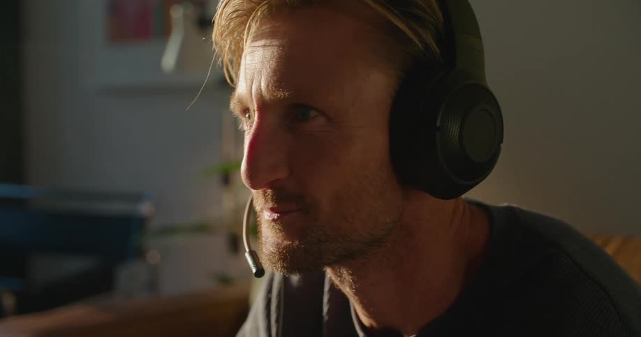 Gamer focuses while talking via gaming headset before cheering