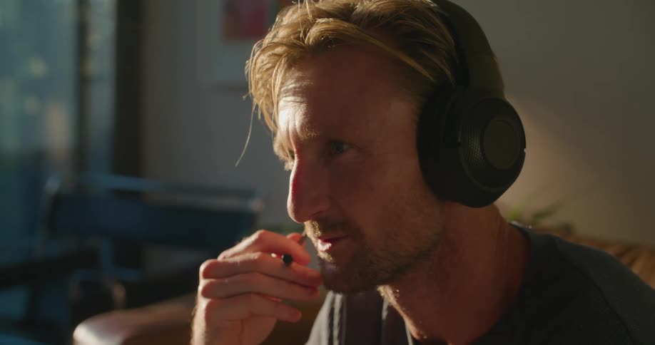 A man is playing video games and sitting in his living room