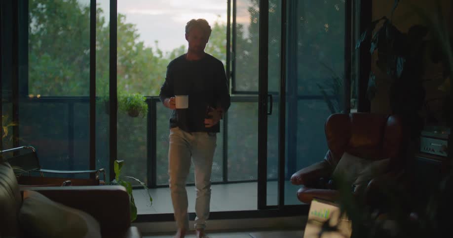 A man ends a conversation on his smartphone and walks inside to work on his laptop
