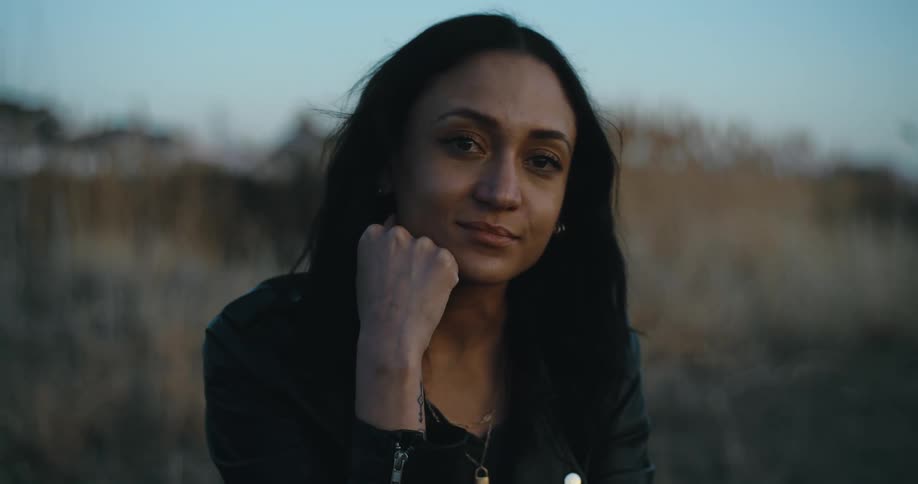 A woman is smiling and sitting outdoors