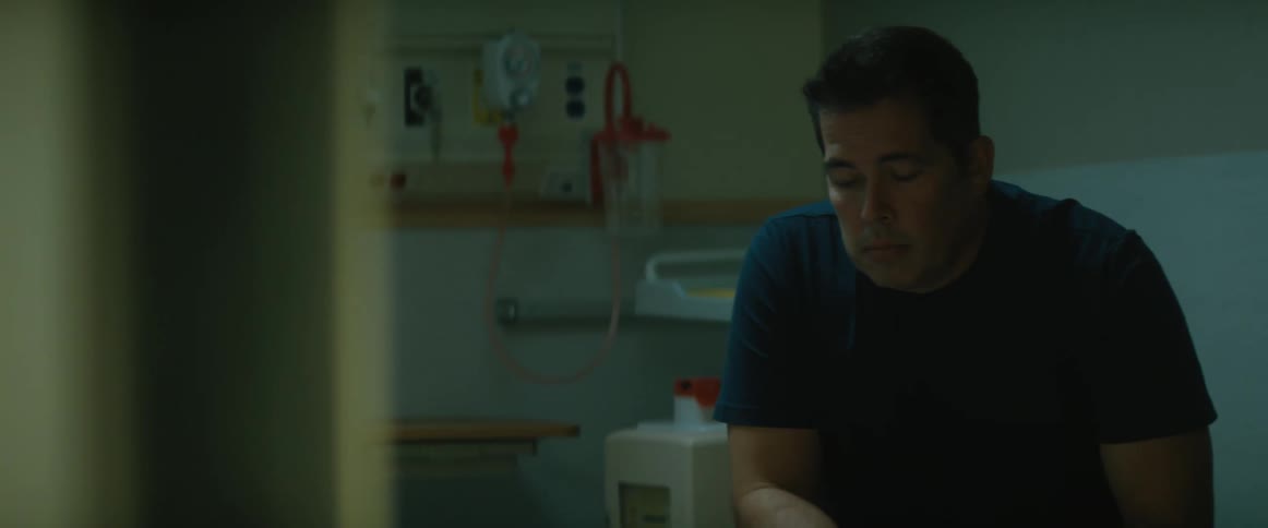 A man grabs his stomach while sitting in a hospital room