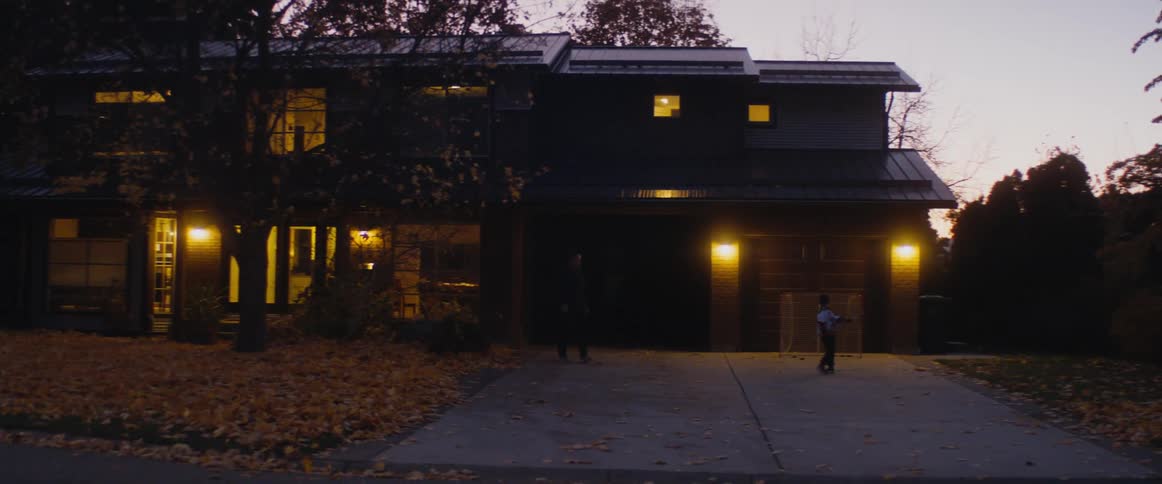 A father walks out of the house to walk with a young boy who was just playing hockey in the driveway