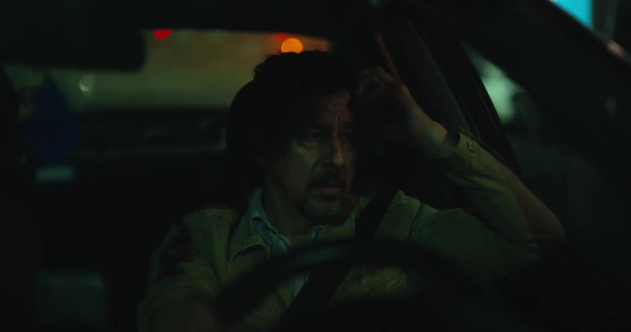 A man is driving an automobile at night and he appears to be tired