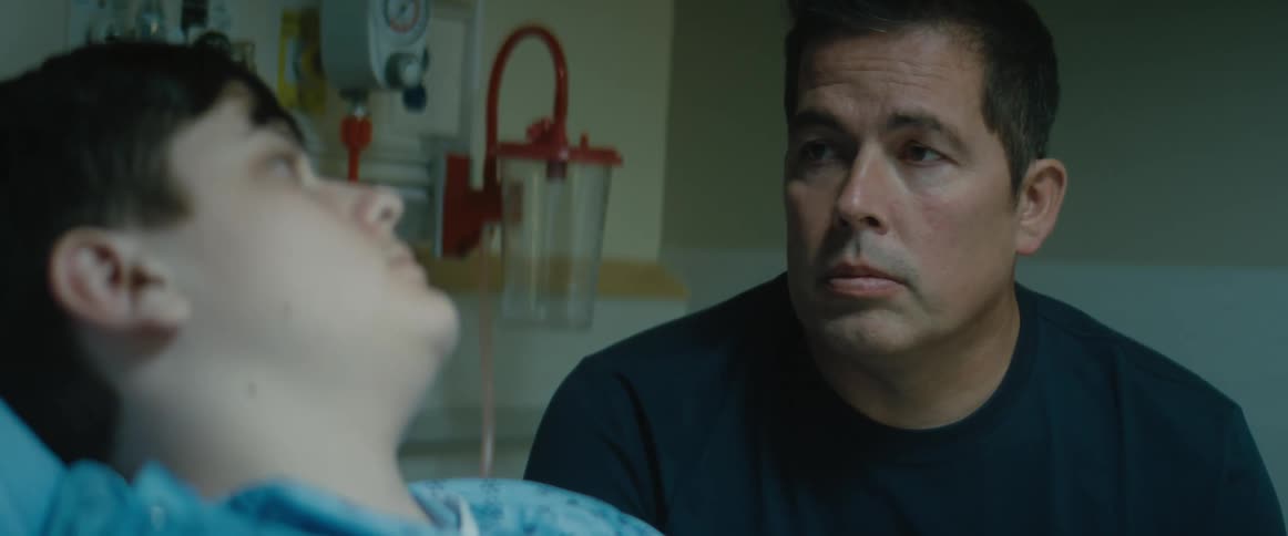 Hospital patient lying in bed turns to meet eyes of male visitor