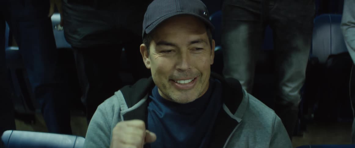 Man quietly cheers while at sports event and remains in his seat as others around him stand