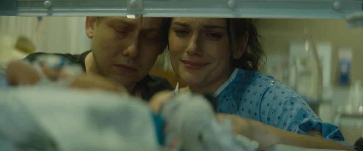 A man and a woman are visiting a baby in the hospital and are very sad