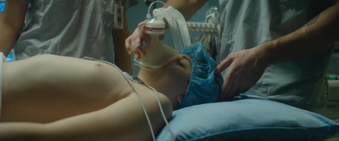 A doctor holds a breathing mask over a young boys face in an emergency room