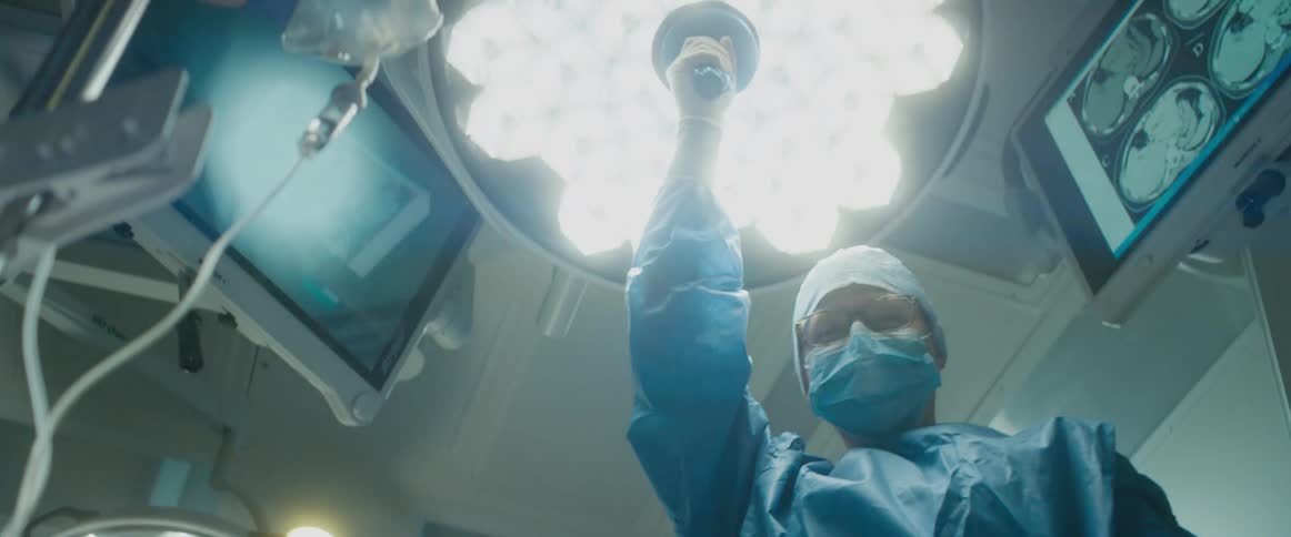 A nurse adjusts the bright light above the patient in an operating room