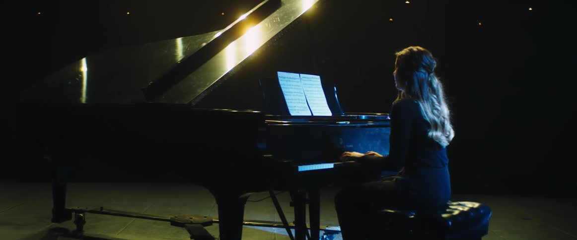 A girl is on stage playing a grand piano
