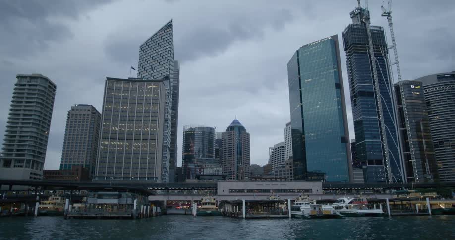 Boats sit docked ina harbor below tall skyscrapers downtown