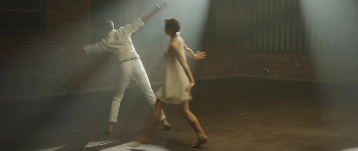 A pair of ballet dancers dance together in an empty room