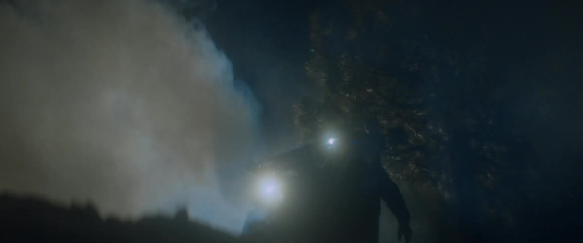 A film crew walks through the fog at night