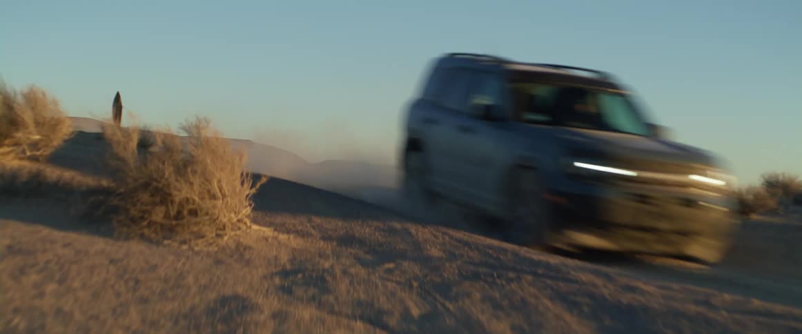 A car is driving on a dirt road in a rural area