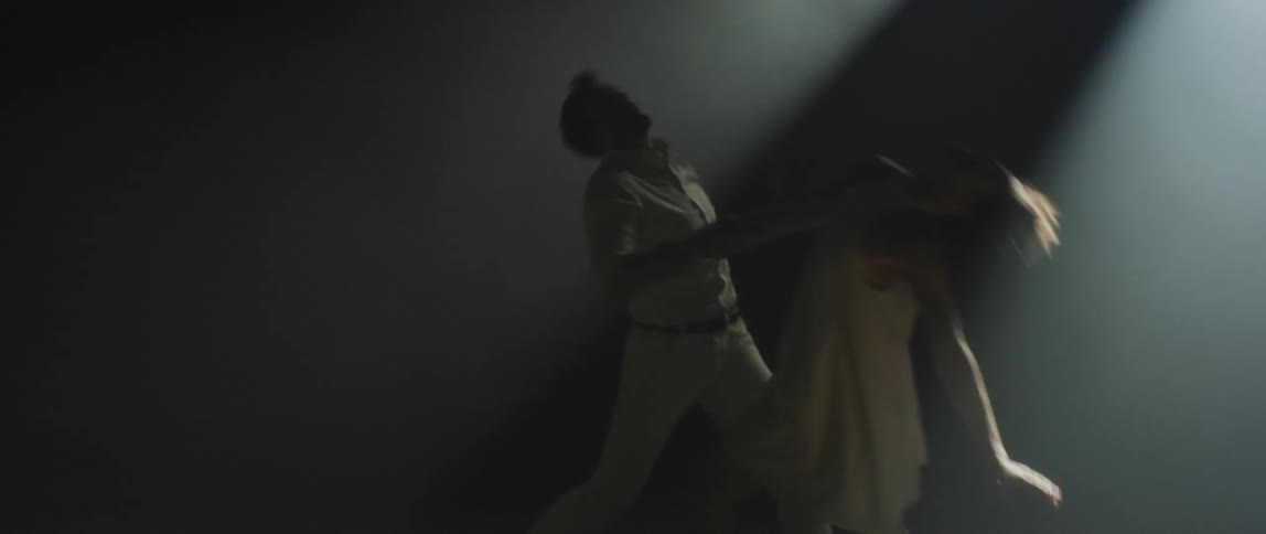 A man and a woman are dancing together as a spotlight shines on them