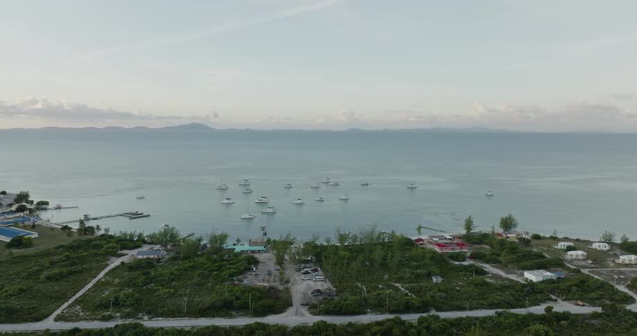 Many boats are sailing off the coast under a hazy sky