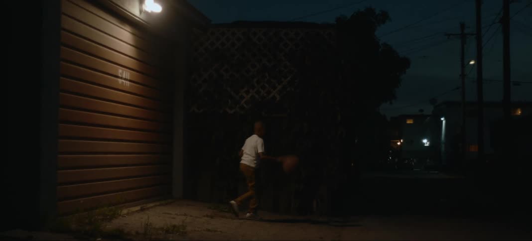 A child is playing basketball at night