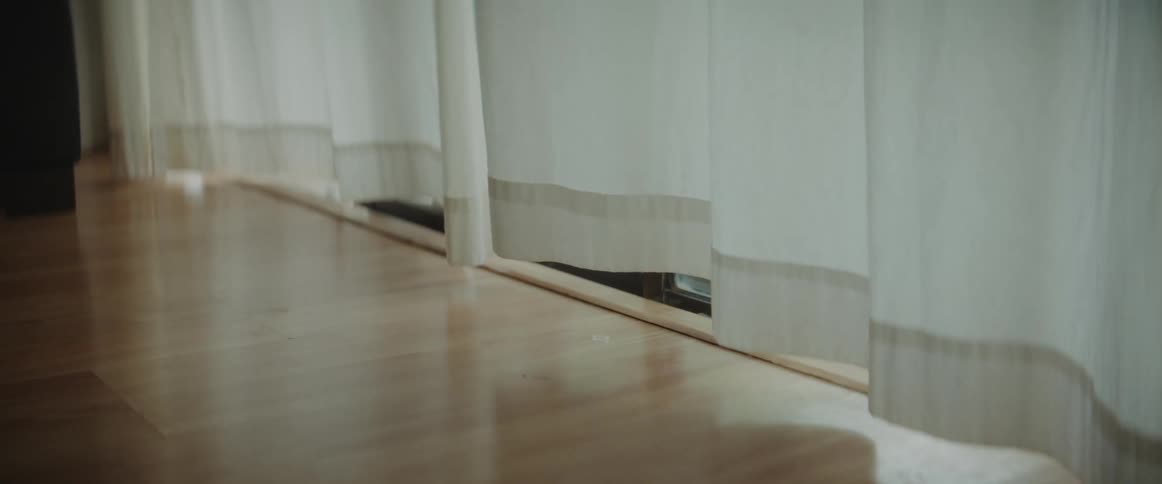A gentle breeze blows onto floor to ceiling curtains in a home