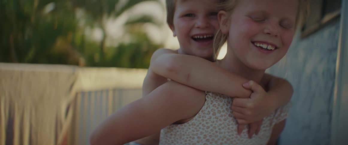 Two kids are playing and the girl is giving the little boy a ride on her back