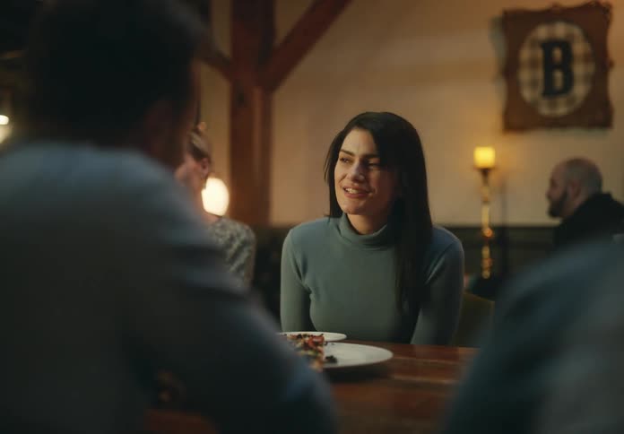 A woman laughs while chatting with friends over a meal at a restaurant
