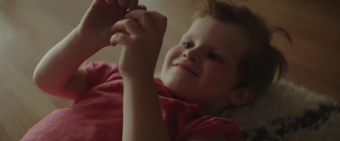 A boy plays with an animal figurine while lying on his back on a rug