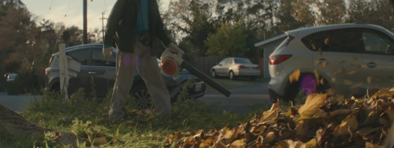 A man is doing yard work outdoors at dusk