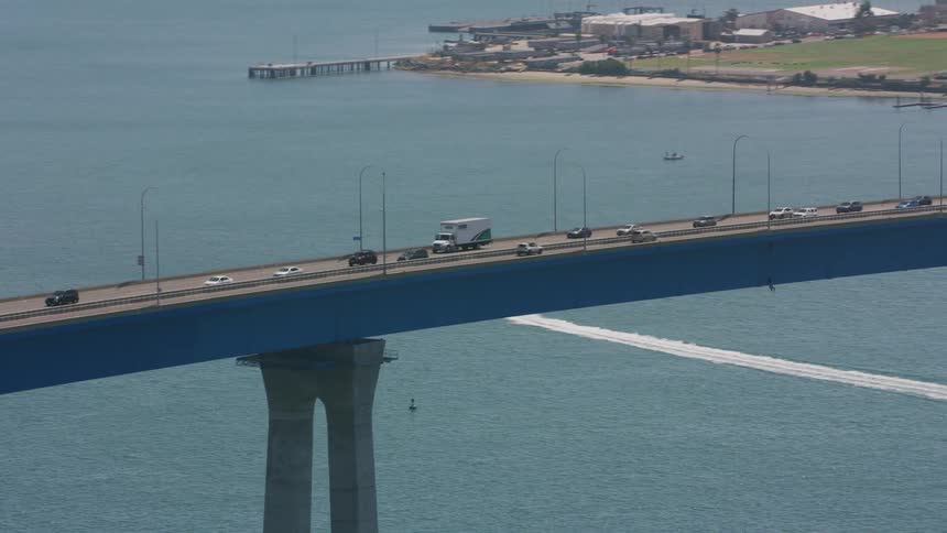 Traffic moves across a bridge as a boat sails on the water below