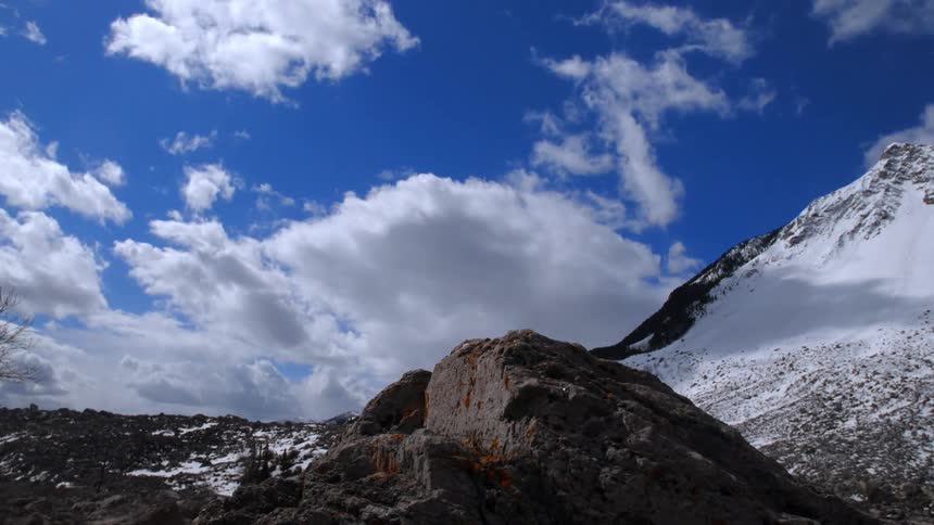 A time lapse of clouds moving over a snow covered mountain