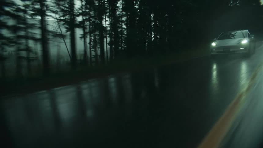 A car drives down a road during a rain storm