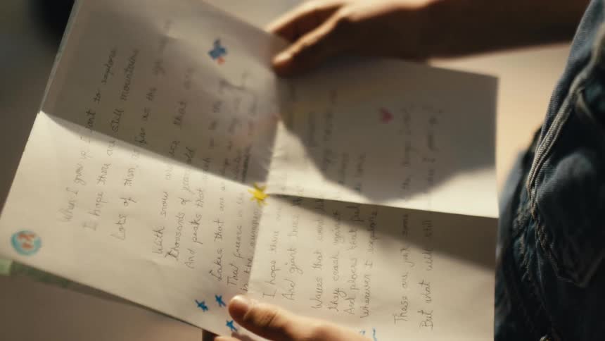 A child is holding a piece of paper with writing on it